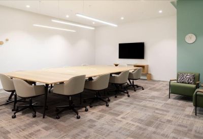 Spacious boardroom with a long light-wood table and wall-mounted TV.