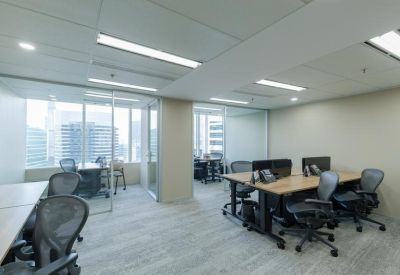 Open-plan workspace with multiple desks, ergonomic chairs, and glass partitions.