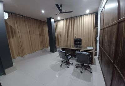 Executive office with a wooden desk, leather chairs, and full-length curtains.