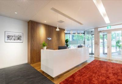 Bright reception area with a sleek white front desk and textured wood wall.