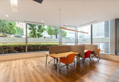 Modern open-plan workspace with orange ergonomic chairs and shared wooden desks.
