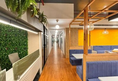 Communal dining area with blue velvet booth seating and warm wooden floors.