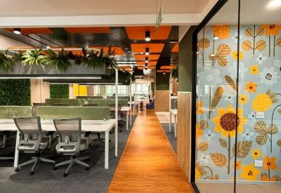 Modern open-plan office with wooden flooring and a floral feature wall.