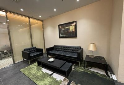 Modern lounge area with black leather tufted sofas and a green patterned rug.