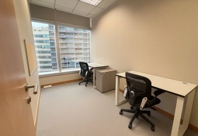 Private two-person office with simple desks and grey storage unit.
