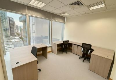 Spacious private office with large corner windows and L-shaped desks.