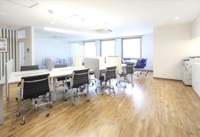 Bright coworking space featuring wooden floors and individual workstations.