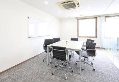 Meeting room with a white table, six black chairs, and a whiteboard.