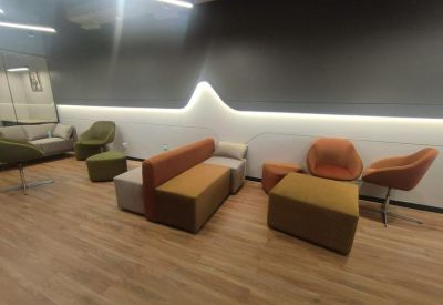 Colorful lounge area with orange and green seating and warm wood flooring.