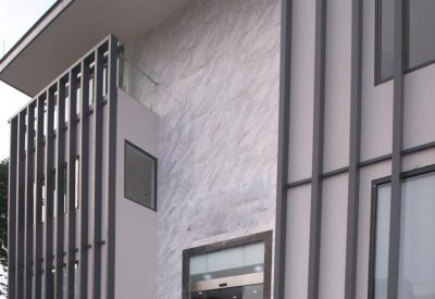 Bright glass entrance featuring marble steps and a ramp surrounded by vertical architectural fins.