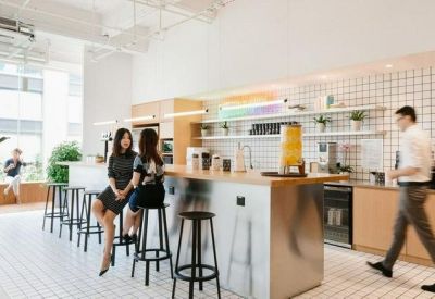 Modern office kitchen and breakout area with a long counter and stools.