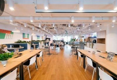 Spacious coworking area with long wooden tables and rows of seating.