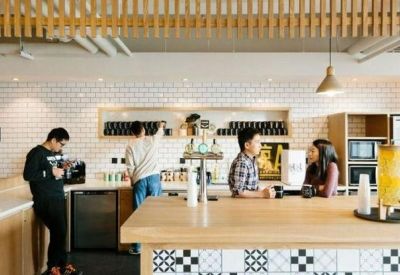 Modern communal kitchen and cafe area with wood-slat ceiling and patterned tile accents.
