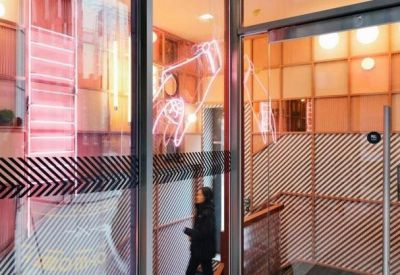 Glass entrance with neon signage and warm wooden wall paneling.