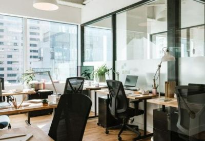 Bright open-plan office with glass partitions, wooden desks, and ergonomic chairs.