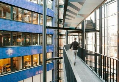 Modern architectural walkway with glass railings overlooking a blue-tiled atrium.
