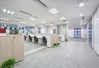 Bright, clinical open-plan office with white desks and ergonomic black chairs.