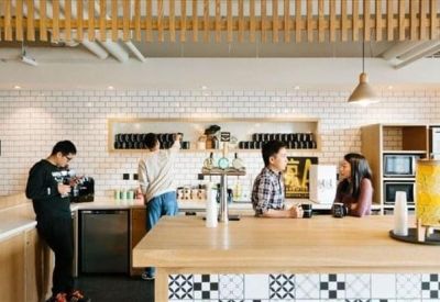 Modern kitchen and cafe area with a white tiled wall and wooden breakfast bar.