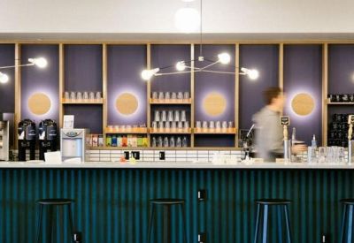 Communal cafe area with a teal-slatted bar and purple-lit shelving.