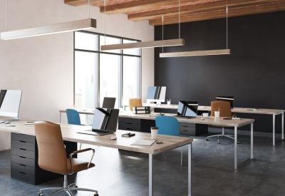 Spacious open-plan office with wooden desks and blue and tan chairs.