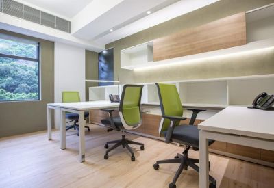 Bright multi-person office suite with white desks and green mesh back chairs.