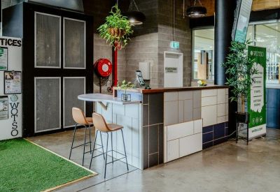Branded reception desk with a mix of tiled patterns, bar stools, and a green wall sign.