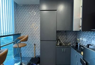 Compact modern kitchenette with patterned floor tiles and grey cabinetry.
