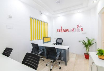 Private office space featuring a white desk, ergonomic chairs, and teamwork wall decals.