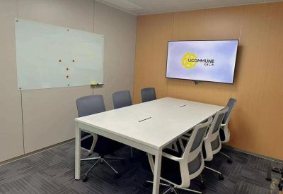 Meeting room with a white table, modern chairs, a whiteboard, and a wall-mounted TV screen.