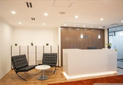Elegant reception area with a white desk and black designer armchairs.