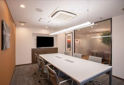 Clean, white conference room with a large rectangular table and wall-mounted screen.