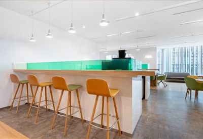 Modern breakroom area featuring a breakfast bar with high yellow stools and green glass accents.
