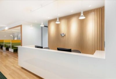 Reception area with a minimalist white desk in front of a decorative light-wood slat wall.