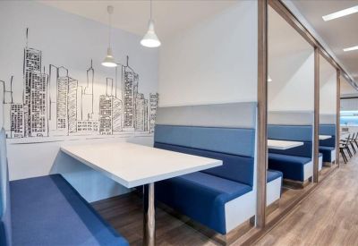 Modern semi-private booths with blue seating and a skyline wall mural.