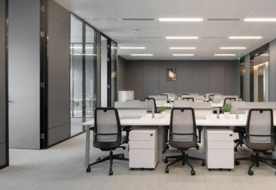 Open-plan office space featuring white workstations and ergonomic mesh chairs.