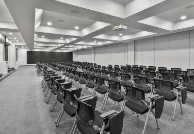 Spacious auditorium-style meeting hall with rows of black chairs and a coffered ceiling.