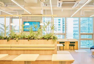 Coworking space featuring built-in wooden bench seating with integrated planters and small café tables.