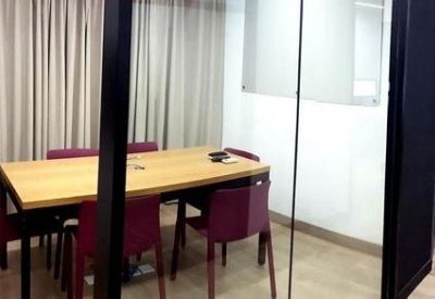 Modern meeting room with a wooden table, burgundy chairs, and glass partitions.