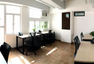 Bright private office suite with multiple desks, ergonomic black chairs, and natural light.