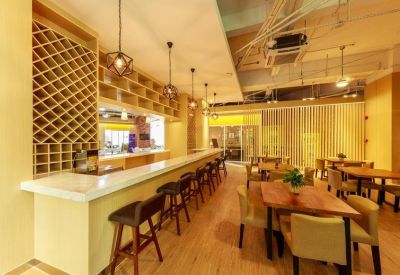 Cafe-style communal area featuring a long white marble bar and wooden dining tables.