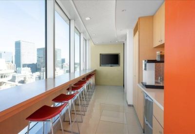 Communal break area with a long window-side counter and red bar stools.