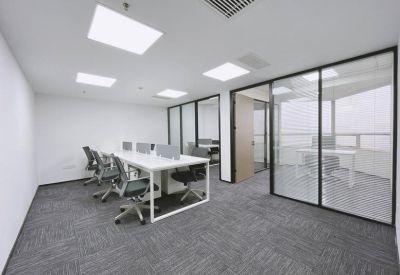 Modern open-plan office with white desks, black chairs, and glass partition walls.