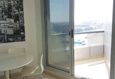 Dining area with white round table and chairs next to a sliding glass balcony door.