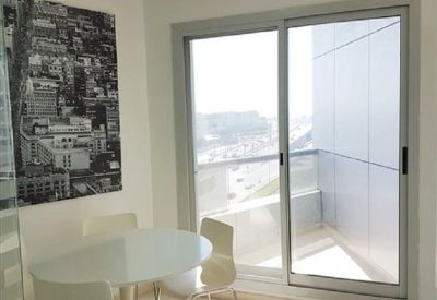 Modern breakout space with a white dining set and city views through large windows.
