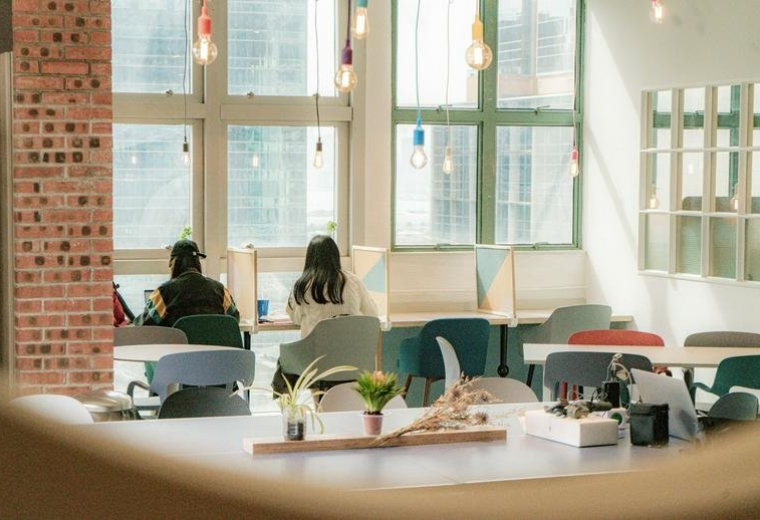 Bright coworking space at Entrepot Centre with colorful seating, large windows, and decorative hanging lights.