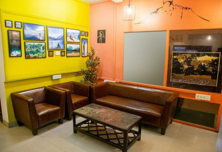 Reception area at 601 B, Annapurna, Adarsh Nagar, Mumbai featuring leather sofas and a yellow feature wall.