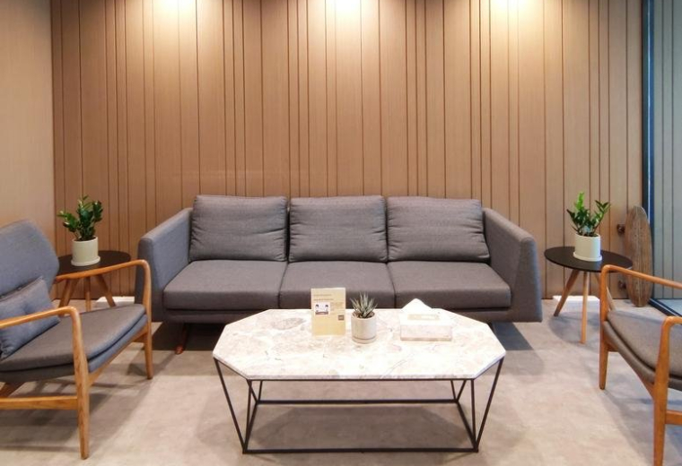Spacious reception lounge at 88 Hing Fat Street with grey sofa, marble table, and wood-paneled walls.