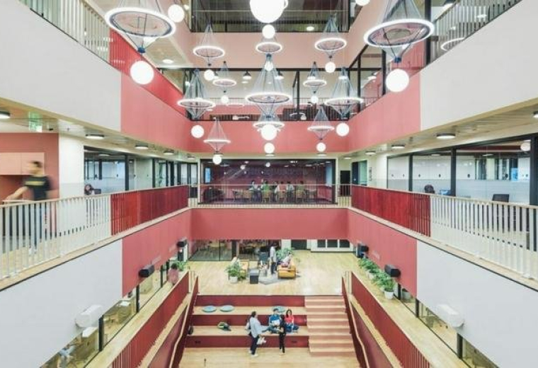 Spacious multi-level atrium at 6 Jiuxianqiao Lu with red accent walls and tiered seating.