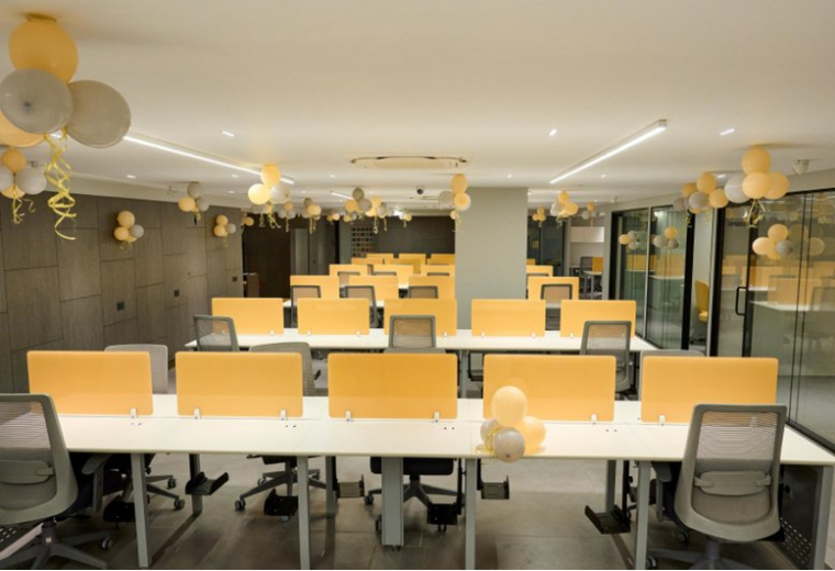 Spacious open-plan office at Anam 2 with yellow partitions and festive balloon decorations.
