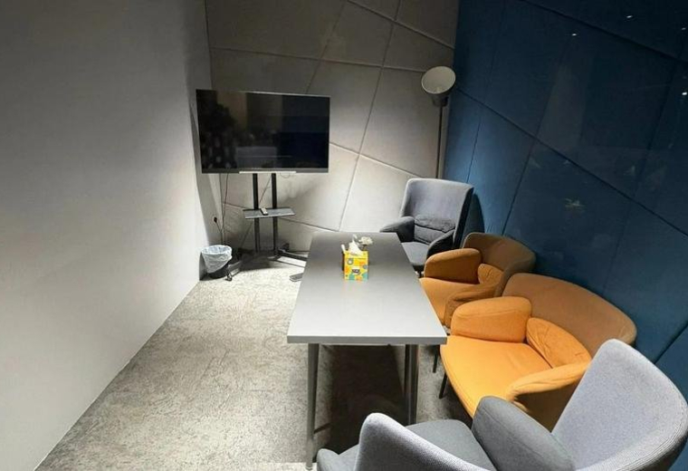Meeting room at King Abdul Aziz Branch Road with a long table, orange armchairs, and a wall-mounted TV.
